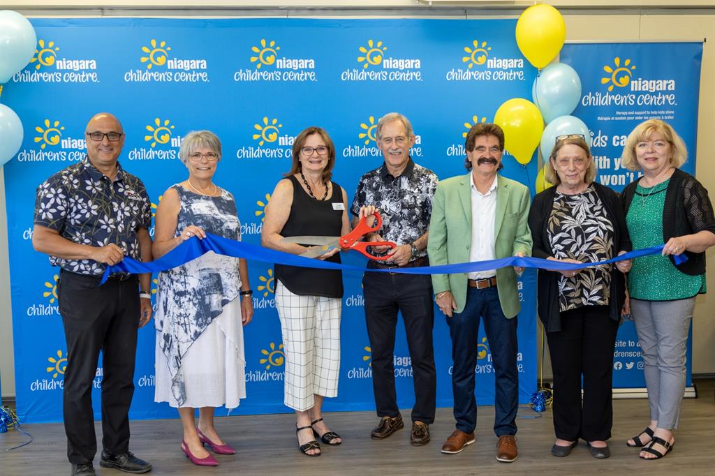 People pose with large scissors and ribbon